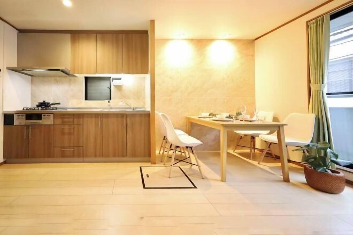 A compact kitchen with wooden cabinets, a gas stove, and a small dining area with a table and chairs.