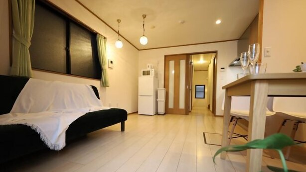 A modern living room with a sofa, a dining table, and a kitchen area with a refrigerator and microwave. - Nagasaki; Ikebukuro 3 min, Shinjuku 11 min, Shibuya 18 min, Ginza 24 min (Tokyo)