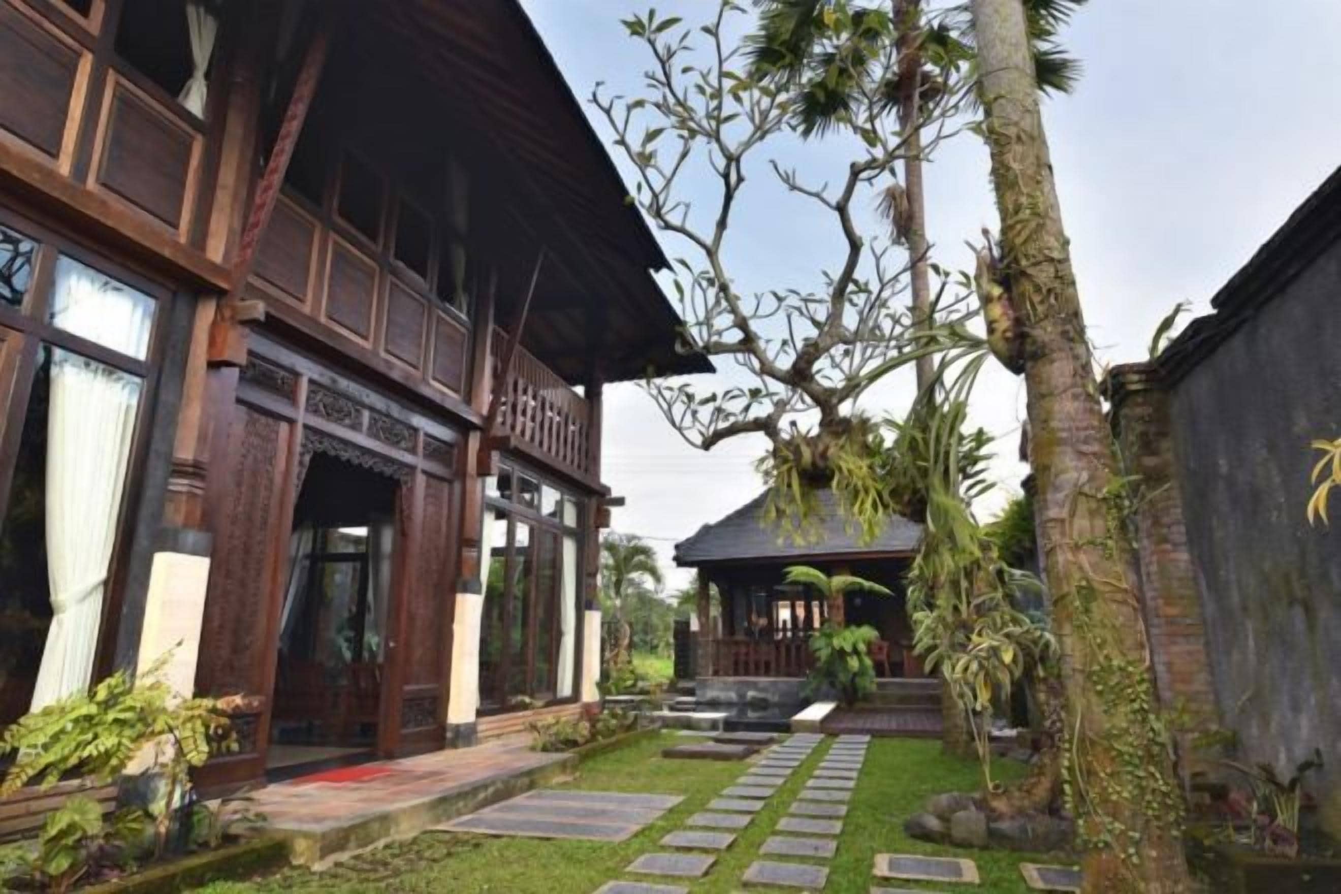 A traditional wooden building with a covered porch and a stone pathway leading to a small structure.