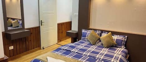 A bedroom with a bed, a mirror, a door, and a wall-mounted light fixture.