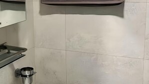 A bathroom with a mirror, a shelf, and a metallic cup holder. - Thamel Holiday Apartments (Kathmandu)