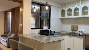 A compact kitchen with a granite countertop, white cabinets, and a built-in microwave. - Thamel Holiday Apartments (Kathmandu)