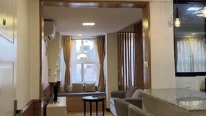 A modern living room with a sofa, a small round table, and a kitchen area with a countertop. - Thamel Holiday Apartments (Kathmandu)
