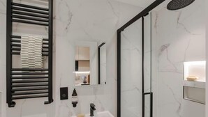 A modern bathroom with a white marble sink, a black towel rack, and a glass shower enclosure. - Kensington Studio B (Lower level) (London)