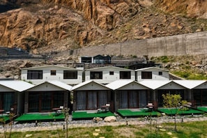A row of white cabins with green roofs, set against a rocky hillside backdrop. - Horizon Resort Hunza (Gilgit)
