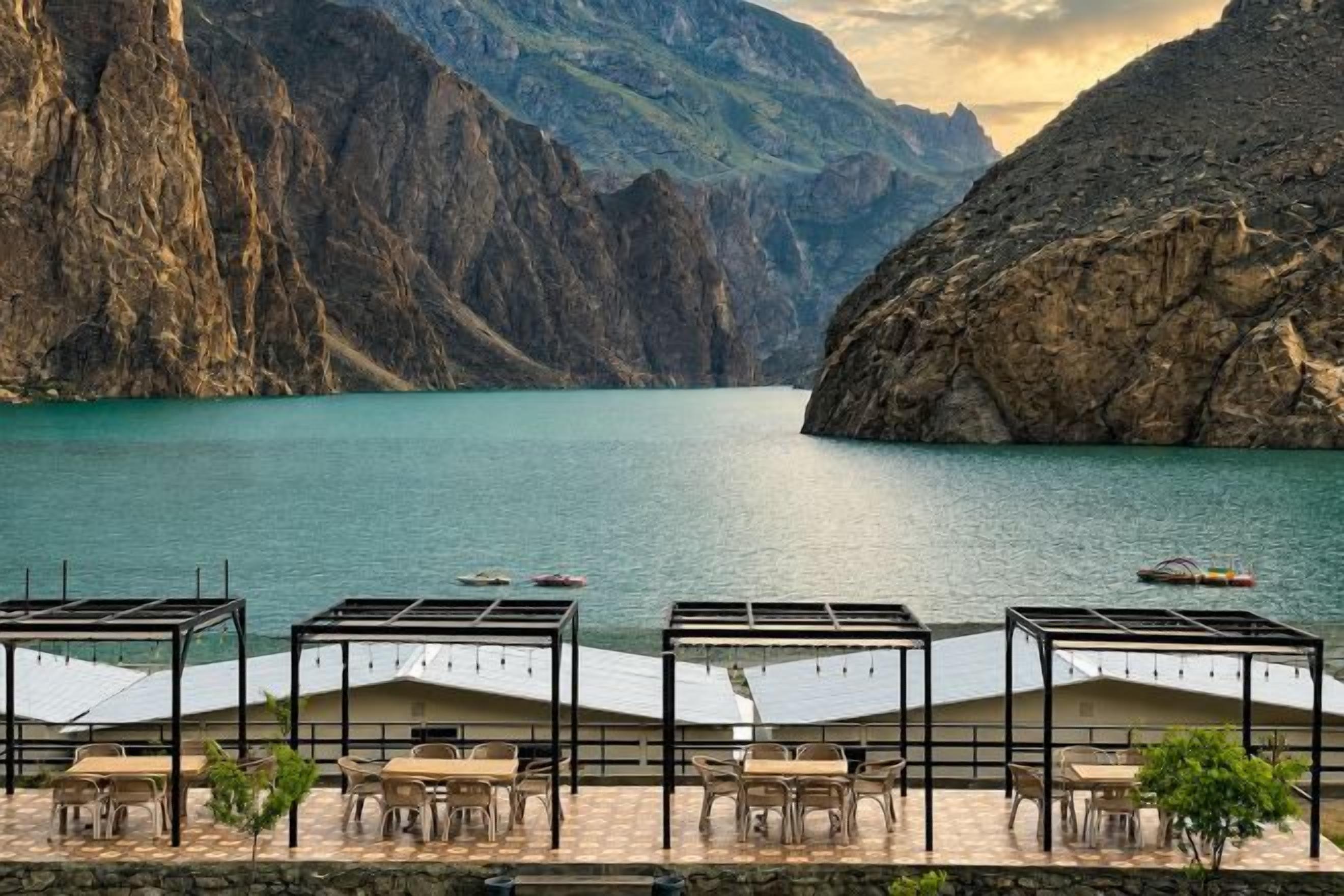 A lakeside terrace with outdoor seating and a view of a mountainous landscape.