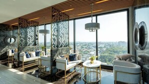 A high-rise hotel room with a city view, modern furniture, and a large window. - Sky RiverPool, Cozy & Luxury for family (Chiang Mai)