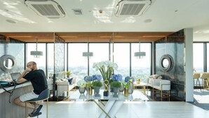 A modern office space with a large desk, a chair, a table with flowers, and a view through large windows. - Sky RiverPool, Cozy & Luxury for family (Chiang Mai)