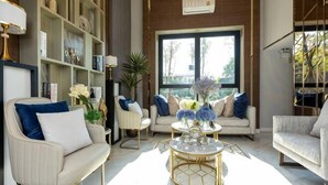 A modern living room with a sofa, armchairs, a coffee table, and a bookshelf. - Sky RiverPool, Cozy & Luxury for family (Chiang Mai)