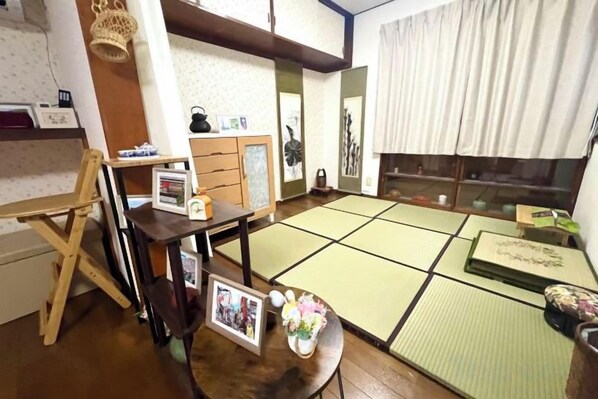 A tatami mat room with a low table, a wooden desk, and a cabinet.