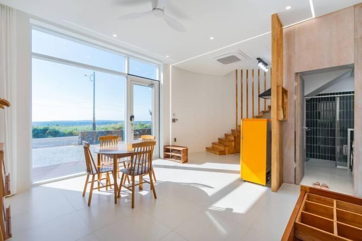 A modern interior with a dining area, a staircase, and a view of the outdoors.