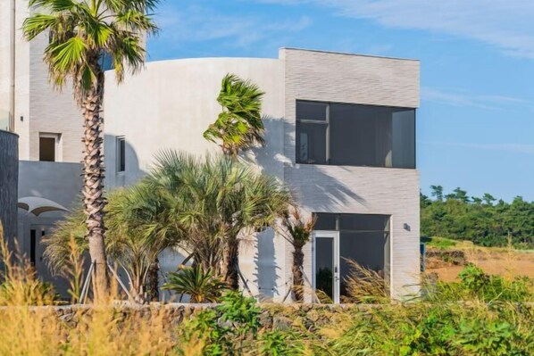 A modern two-story building with a flat roof, large windows, and a door.