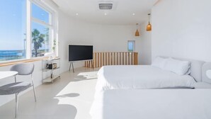 Una habitación de hotel moderna con una cama grande, un escritorio con silla, televisión y vista al mar.