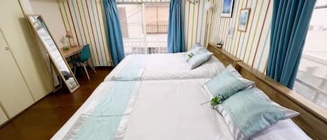 A hotel room with two beds, a desk, and a window with curtains.