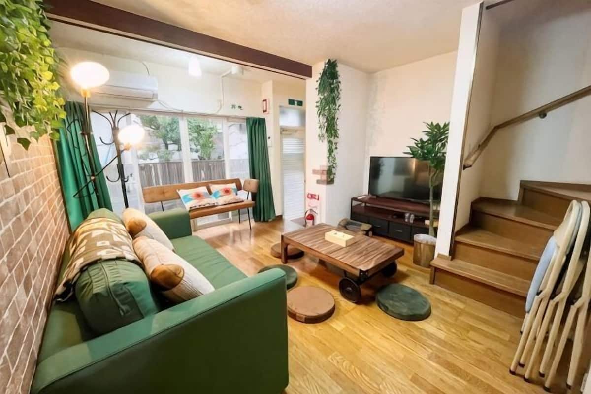 Ein Wohnzimmer mit Sofa, Couchtisch, Fernseher und Treppe.