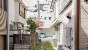 A narrow alleyway with a pathway, a wooden fence, and a parked car. - Yokohama Chuo 2 House (Yokohama)