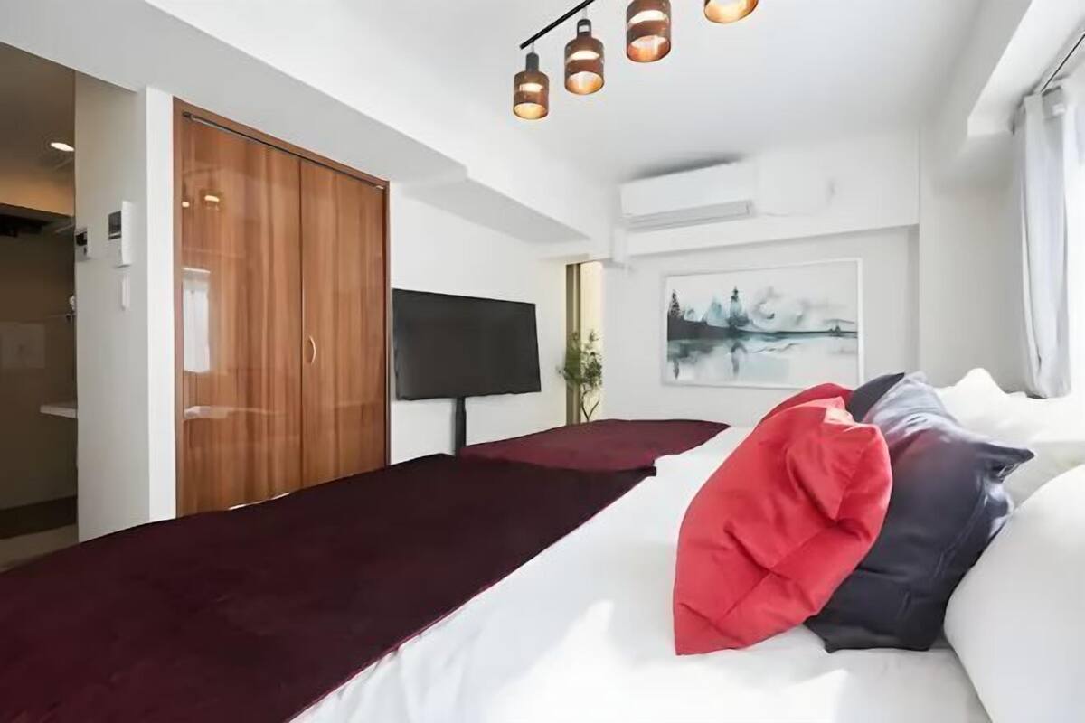 A modern bedroom with a bed, a TV, and a wooden wardrobe.