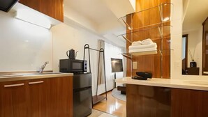 Cocina moderna con armarios de madera, microondas integrado, refrigerador y repisa de vidrio con toallas.
