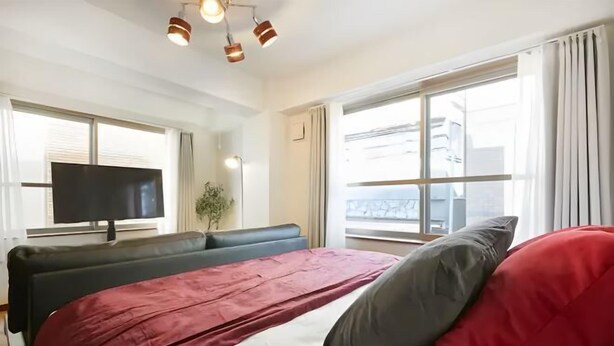 Una habitación de hotel con una cama, un televisor y ventanas amplias.