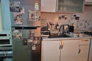 Una cocina con refrigerador, lavamanos y armarios.
