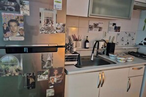 Una cocina con refrigerador, pileta y alacenas.