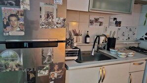 A kitchen with a refrigerator covered in photos and notes, a sink with a faucet, and various kitchen items on the countertop. - 3 minutes Seoul Station by AREX from Incheon Airport, luggage storage breakfast included (Seoul)