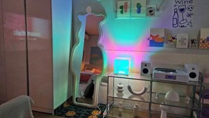 A room with a mirror, a bed, a bedside table with speakers, and a wall with framed artwork. - 3 minutes Seoul Station by AREX from Incheon Airport, luggage storage breakfast included (Seoul)