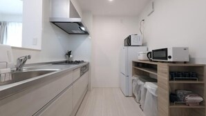 Μια μικρή, λειτουργική κουζίνα με νεροχύτη από ανοξείδωτο ατσάλι, γκαζιέρα, φούρνο μικροκυμάτων και ψυγείο.