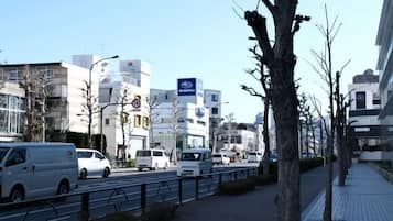 A city street with buildings, a sidewalk, and vehicles.