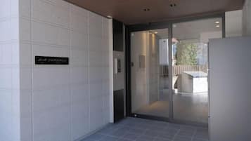 A hallway with a glass door leading to a seating area, a sign indicating 'South Entrance,' and a tiled floor.