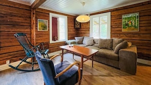 A cozy log cabin interior with a rocking chair, a sofa, and a wooden table. - 2 bedroom gorgeous home in Rottneros (Rottneros)