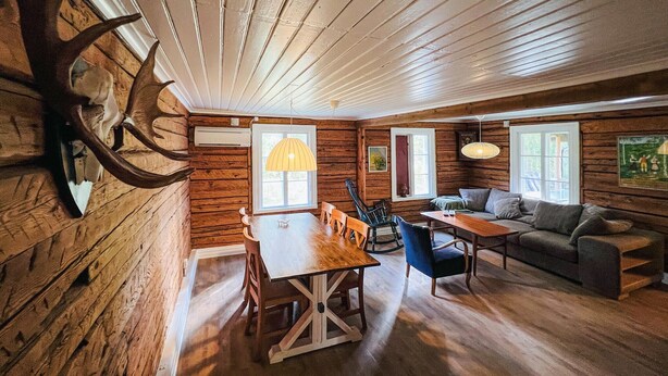 A log cabin interior with a dining table, chairs, a sofa, and a chandelier. - 2 bedroom gorgeous home in Rottneros (Rottneros)