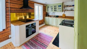 A compact kitchen with wooden walls, a built-in stove, and a window. - 2 bedroom gorgeous home in Rottneros (Rottneros)