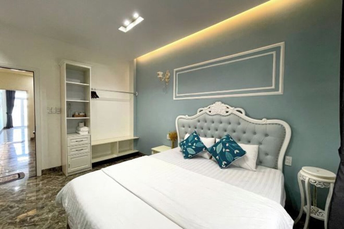 A bedroom with a bed, a wardrobe, a bedside table, and a nightstand.