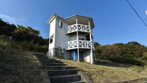 A two-story building with a white exterior and a balcony on the upper floor. - Ultra Private Off Grid Island Villa Near the Beach Mandarin Farm Setting (Bizen)
