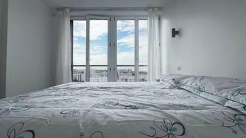 Une chambre avec un grand lit, une vue par la fenêtre et un panorama sur la ville.