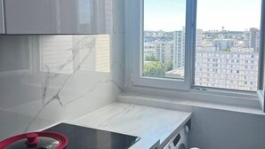 Una cocina moderna con un amplio ventanal, encimera de mármol y vistas a un paisaje urbano.
