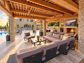 An outdoor patio with a stone fireplace, outdoor seating, and a pool in the background. - Keur bouyo - Provençal Luxury Retreat (Saint-Saturnin-lès-Apt)