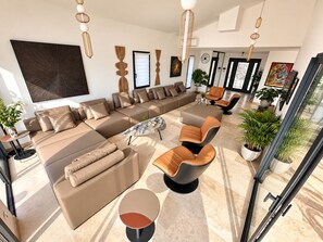 A modern living room with a sectional sofa, a coffee table, and a glass door leading to a balcony.
