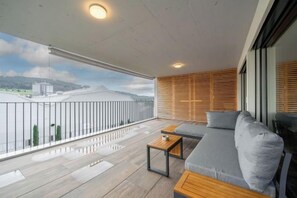 Un balcon avec un canapé et une table, une vue sur la ville et un mur en bois à lattes.