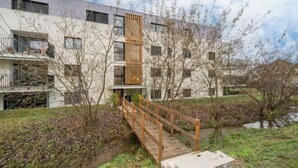 A modern building with a wooden bridge leading to a balcony.