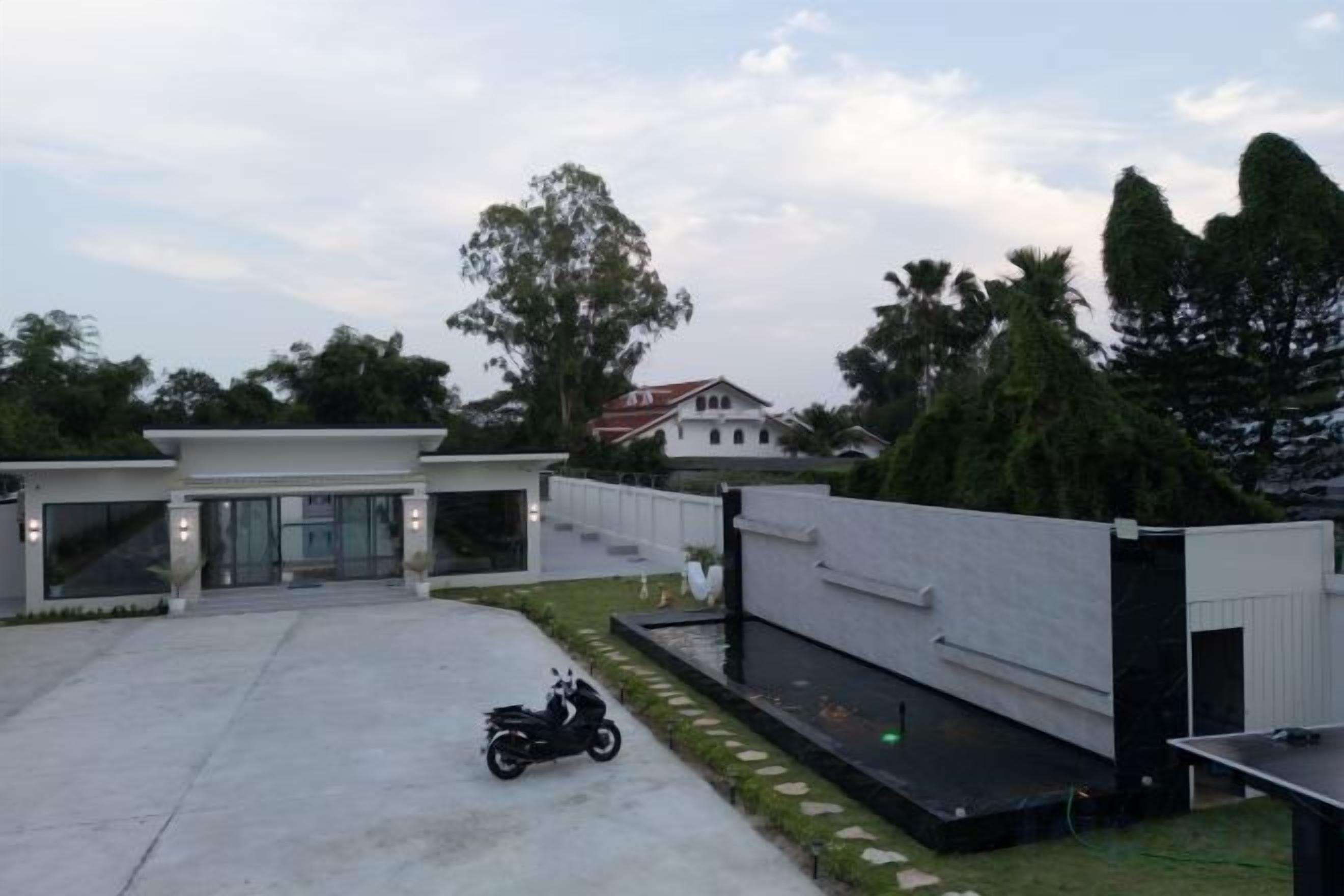 A modern building with a paved driveway, a motorcycle, and a small pool area.