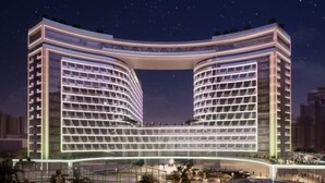 Ein modernes Hotel mit einer markanten, gebogenen Fassade, mehreren Stockwerken und einem zentralen Atrium.