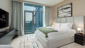 Ein modernes Hotelzimmer mit einem großen Bett, einem Fernseher und Blick auf die Stadt durch ein großes Fenster.