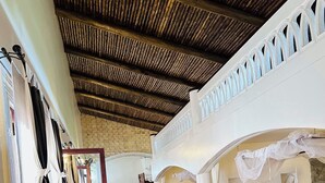 A spacious room with a high ceiling, a wooden floor, and a balcony with white railings. - Villa Jahawi (Diani Beach)
