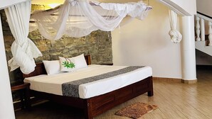 A bedroom with a bed under a canopy, a stone wall, and a wooden floor. - Villa Jahawi (Diani Beach)