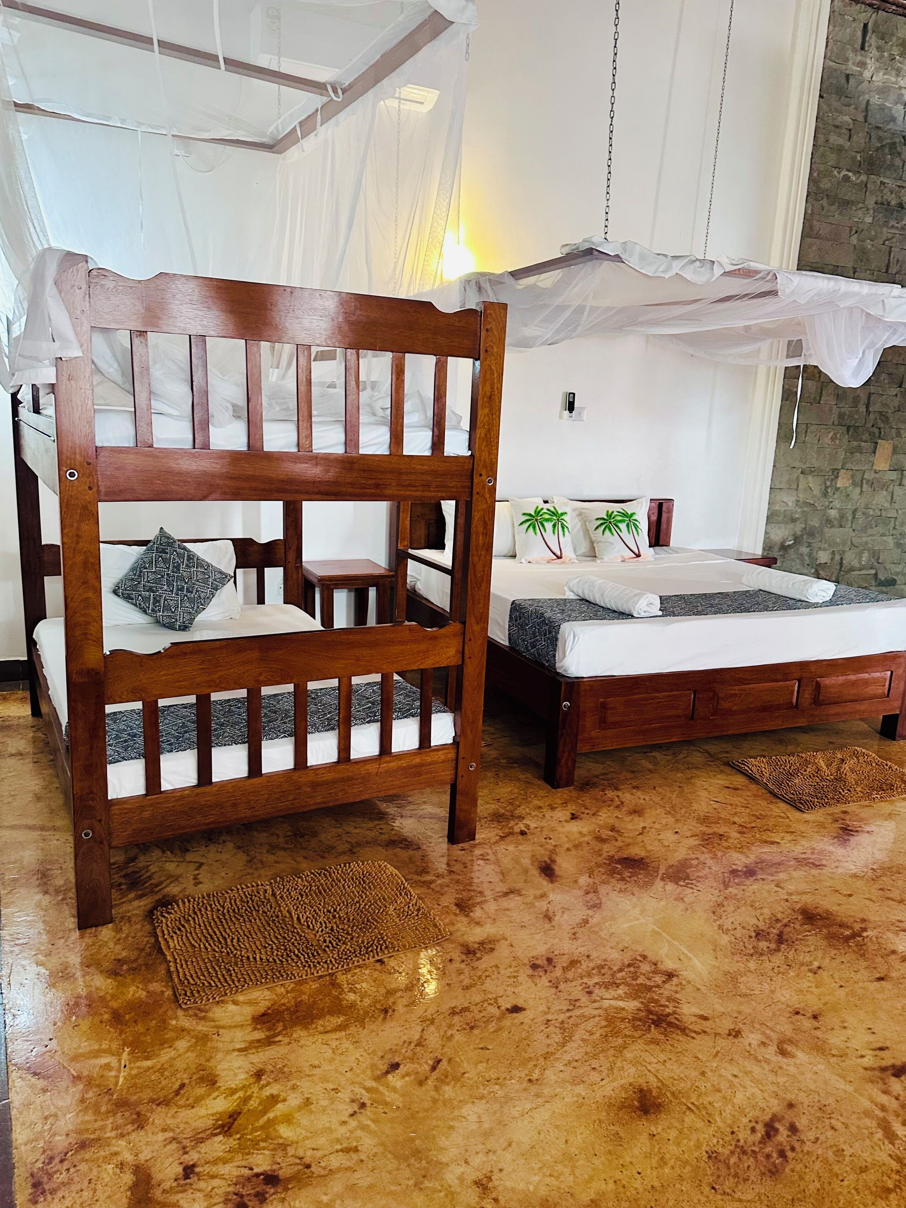 Un dormitorio con estructura de cama de madera, dosel y pared de piedra.