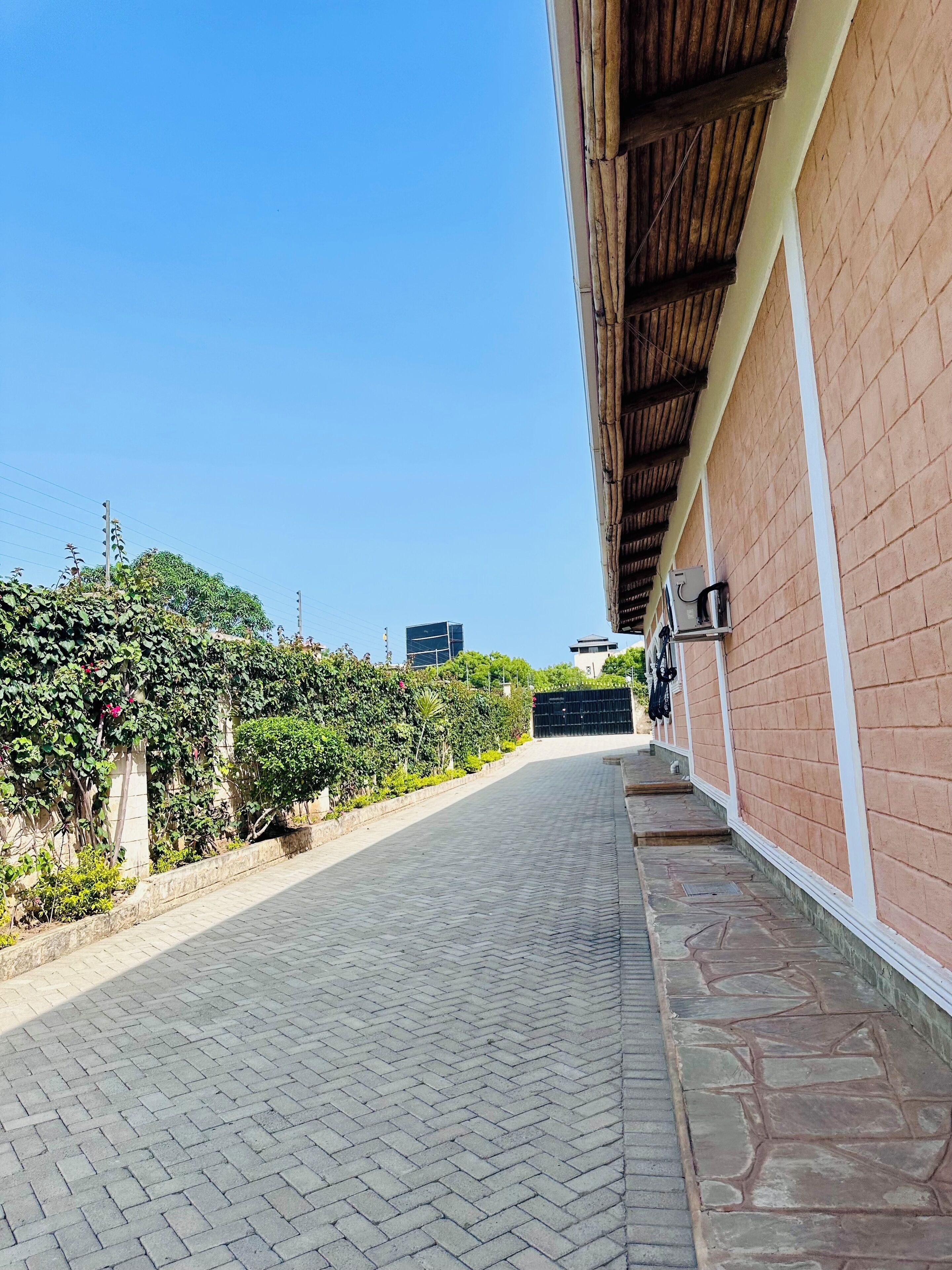 A paved pathway leading to a building with a brick exterior and a wooden roof.