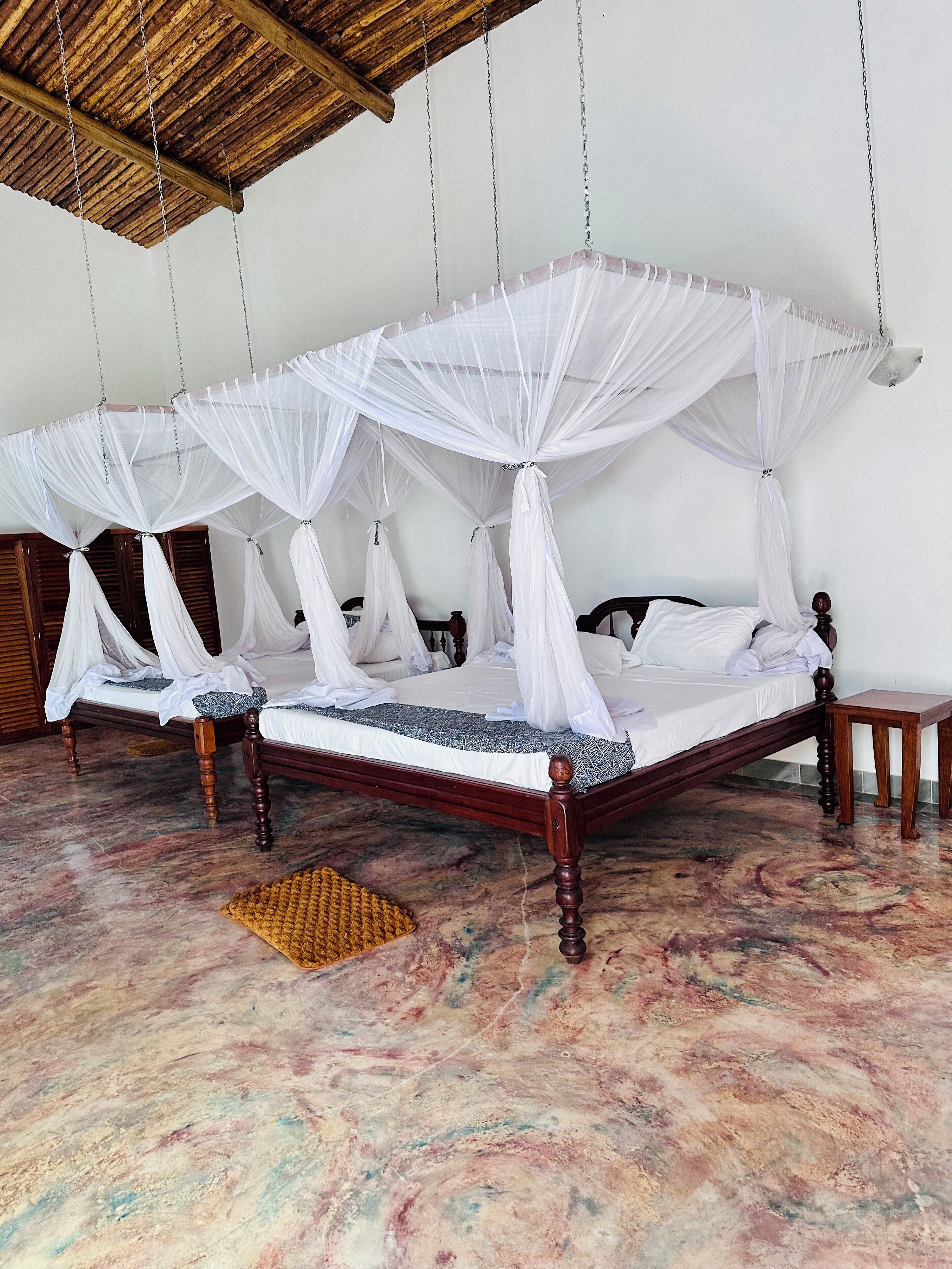 A room with two wooden beds, each with a canopy.
