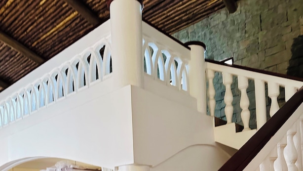 A spacious bedroom with a large bed, a wooden headboard, and a stone wall. - Villa Jahawi (Diani Beach)